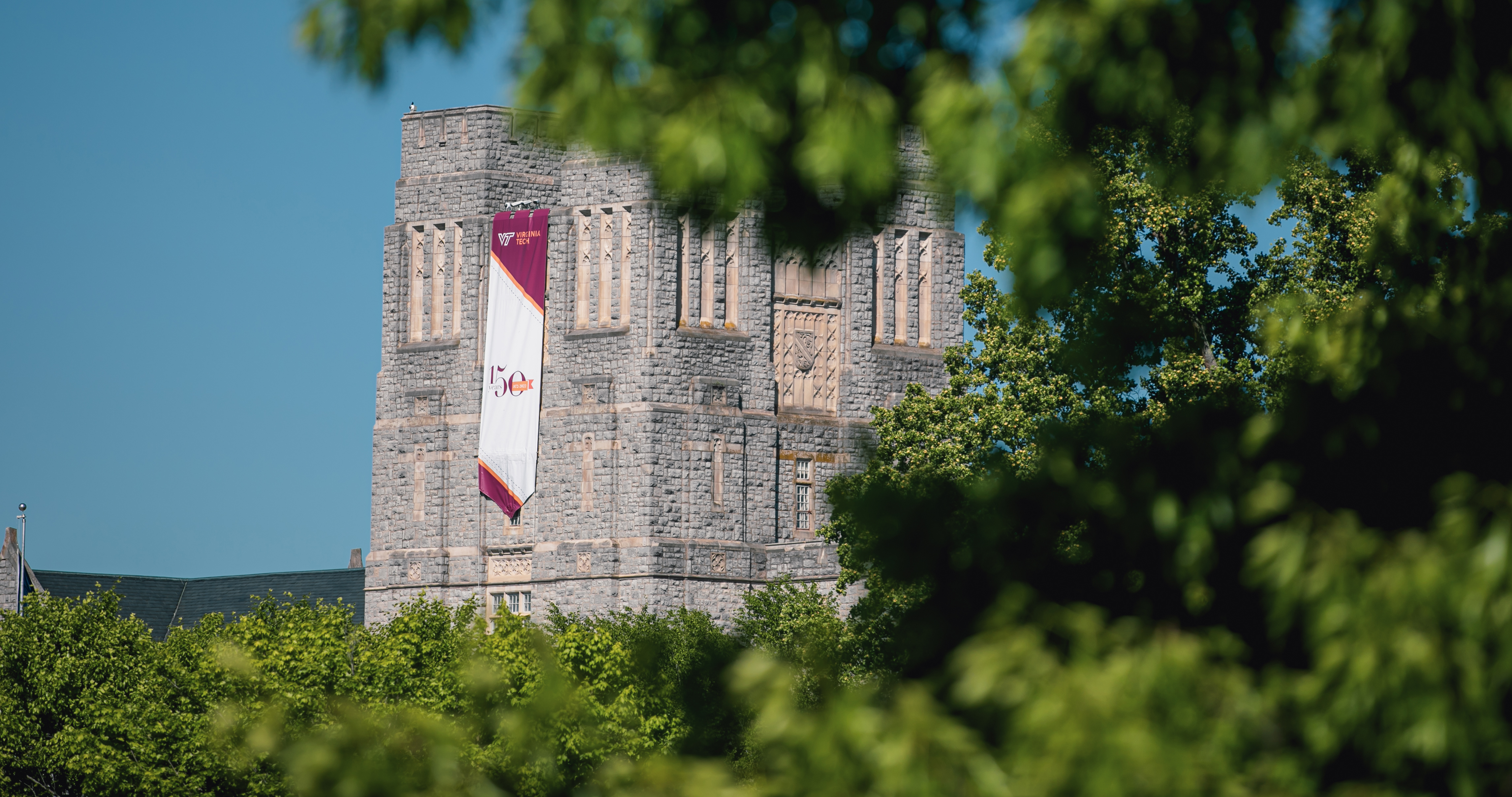 Burruss Hall with Sesquicentennial Banner behind Campus Trees